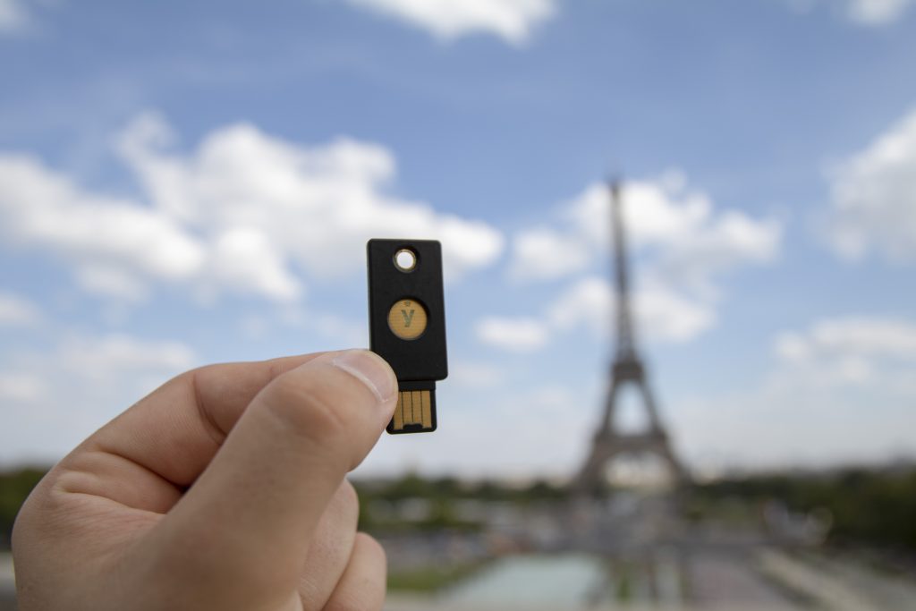 hand holding YubiKey with eiffel tower in background