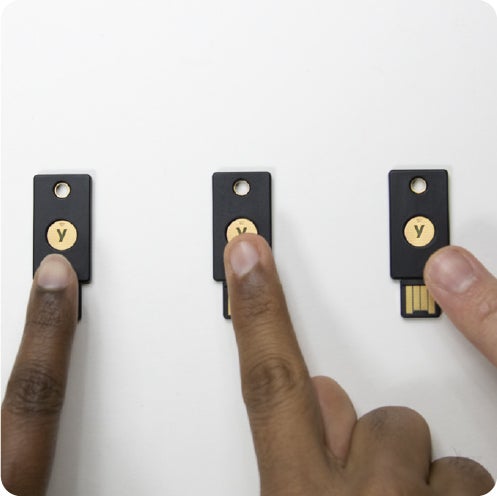 Fingers touching YubiKeys