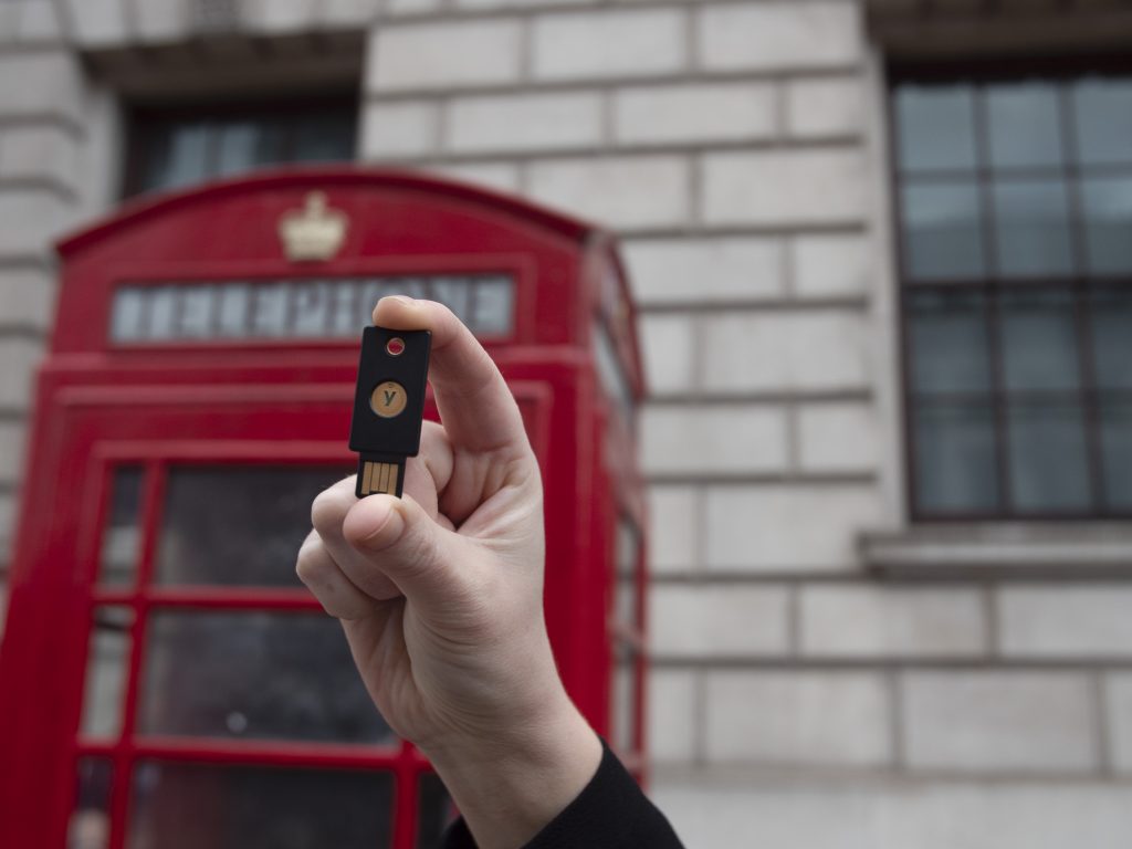 hand holding YubiKey in front of a red phone booth