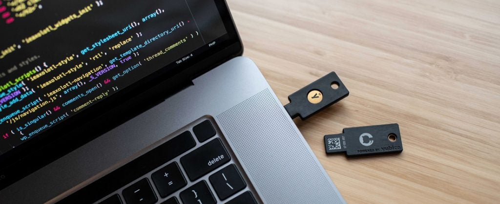 YubiKey on a desk next to a laptop with another YubiKey plugged in