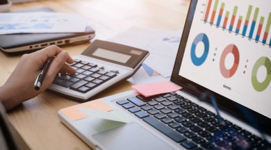 Worker with a calculator and laptop with a spreadsheet