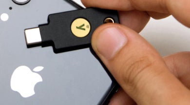 Hand holding YubiKey behind Apple iPhone