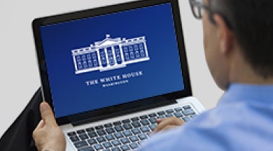 Person looking at a computer with a government building showing